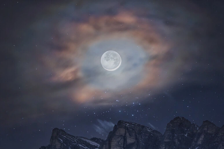 Un'aureola di nuvole per la Luna sopra le cime delle Dolomiti